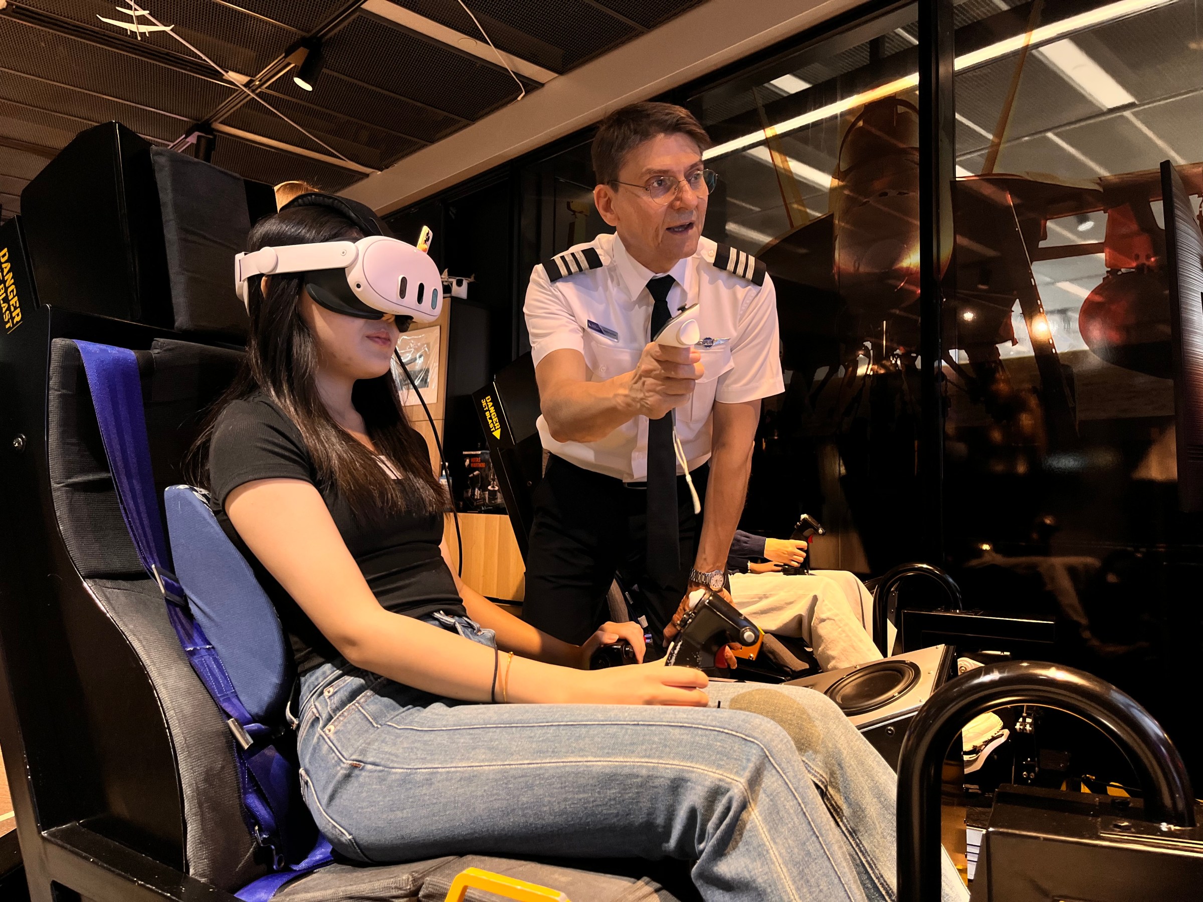 Person in VR headset with an instructor in a flight simulator.