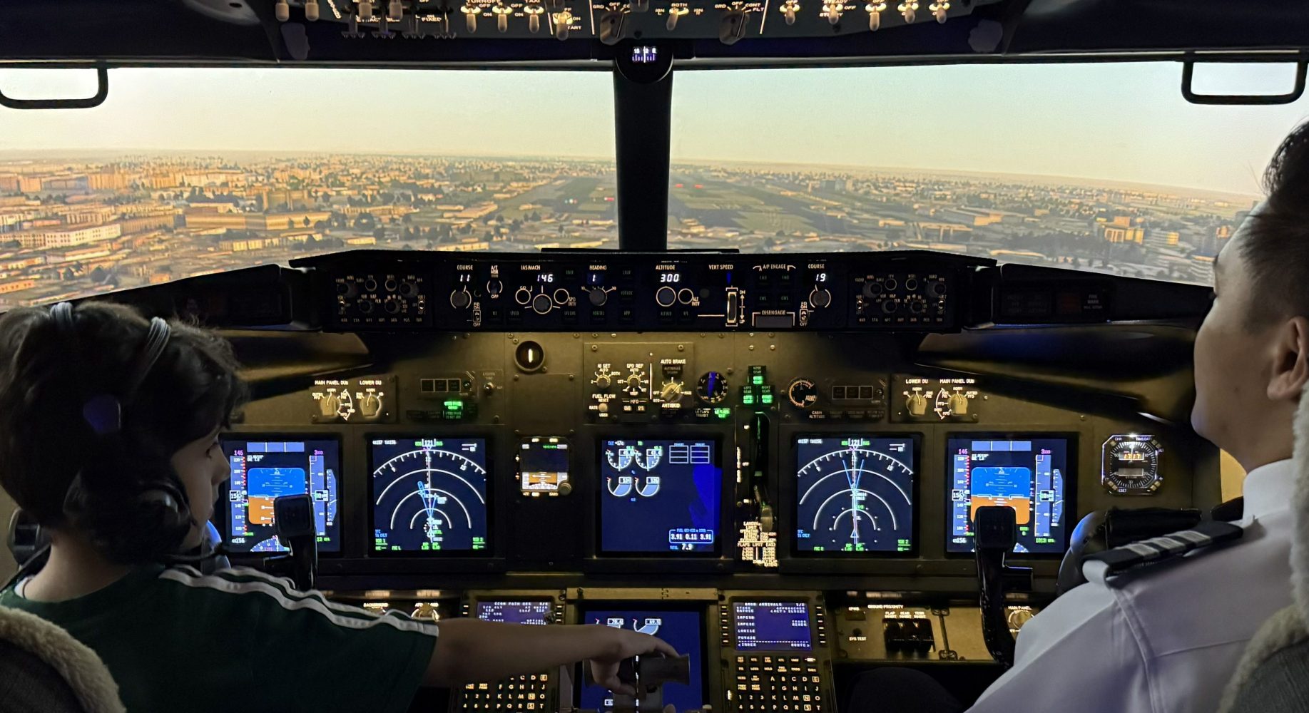 Child and pilot in airplane cockpit during flight simulation.